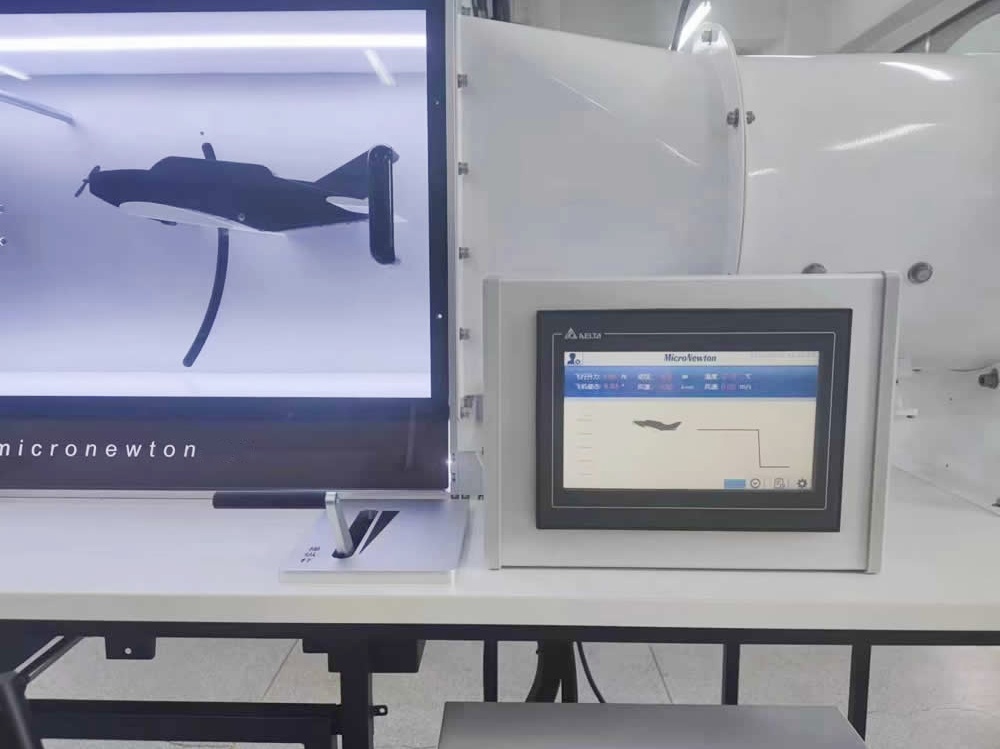 student operating the flight demonstration wind tunnel control stick beside the digital twin display at Shandong University
